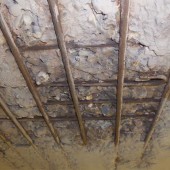 Betonschade door carbonatatie in kelder ter hoogte van het plafond.